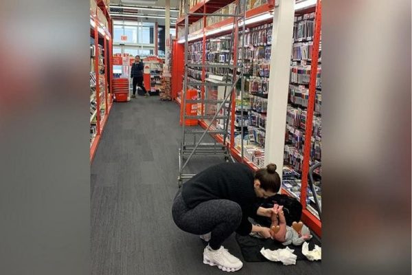 Model AS Ashley Graham mengganti popok bayi laki-laki di lantai toko peralatan kantor Staples